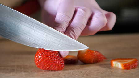 closeup of chef cook cuts strawberries on a cutting board