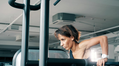 Athletic woman in sportswear is doing push-ups on parallel bars in gym. Sport and bodybuilding...