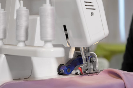 Processing tissue of fabric edge. Seamstress working at sewing machine making stitches seams with...