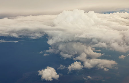 Aerial view from the plane of white soft fluffy clouds over the green landscape in sky in sunny day, tonedの写真素材