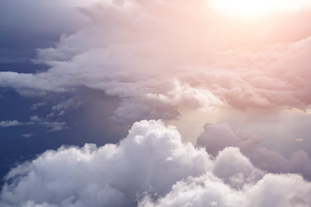 Aerial view from the plane of white soft fluffy clouds over the green landscape in sky in sunny day....