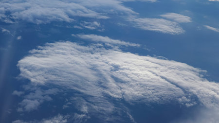 Aerial view from the airplane. Flying over the layer of clouds and looking on landscape through the...