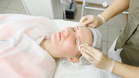 beauty salon therapist in white sterile gloves rinses patient face after laser hair removal close viewの写真素材