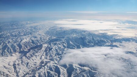 Beautiful view through airplane window, airplane flying above the mountains with clouds.の写真素材