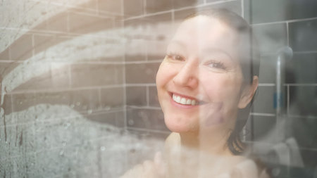 attractive lady with long wet hair smiles from shower glass door