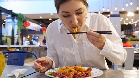 Young woman eating thai noodles with chopsticks.の写真素材