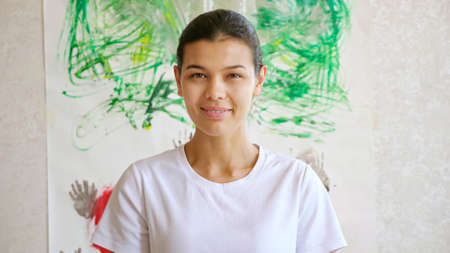 concentrated woman artist in white t-shirt smiles standing against masterpiece on wall of local art gallery under summer sunlight closeupの写真素材