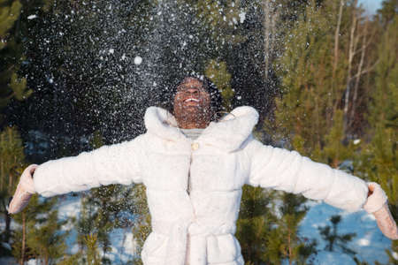 Dark-skinned woman plays with snow on a frosty afternoon.の写真素材