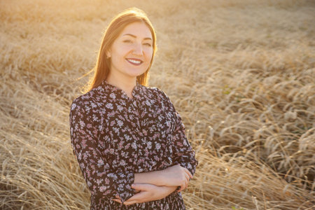 Brunette woman stands in a wheat field sunlight, copyspace