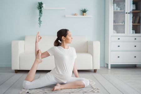 Calm pregnant woman does ardha matsyendrasana pose at home.