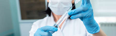 medical worker with gloves draws a medicine from an ampule into a syringe.の写真素材