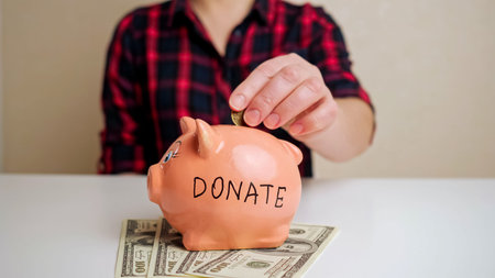 Piggy bank with Donate inscription stands on dollar banknotes and white surface against woman in...