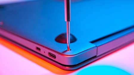 Close-up of screwing bolt into laptop cover in red blue light.の写真素材