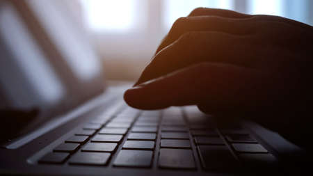 Close up of hands of woman types on laptop in low lightの写真素材