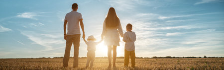 panoramic view of family with children sons stands joining hands at sunset backside viewの写真素材