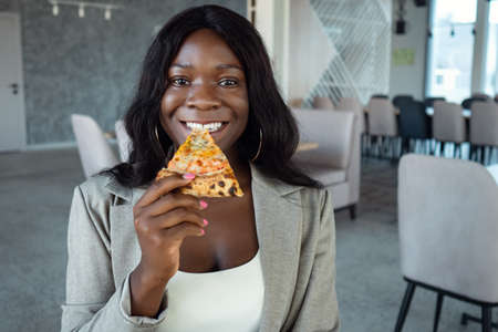 african american woman in business suit eating pizza.の写真素材