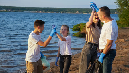 family of four with teenagers clearing the beach from plastic debris. Environmental education...