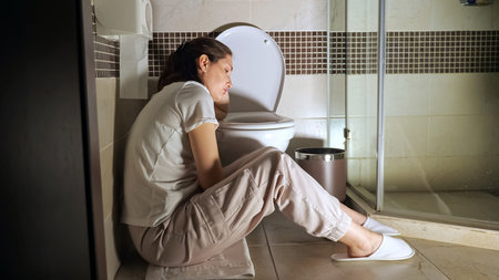 Young woman sitting near toilet, poisoning, toxicosis.
