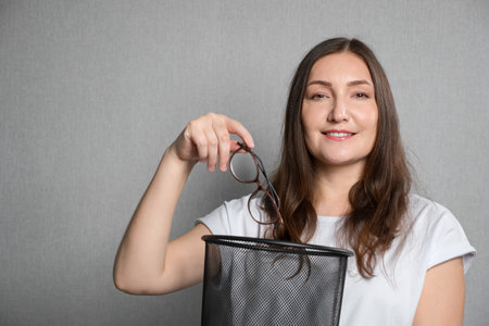young woman throws glasses in the trash can, close upの写真素材