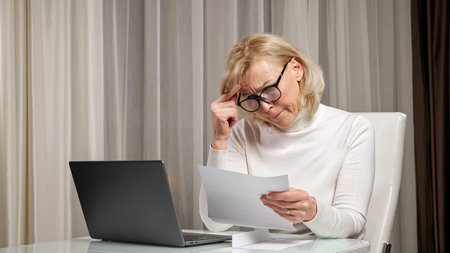 Blonde long-haired dame with bangs and light natural makeup in turtleneck reads letter with bad news...