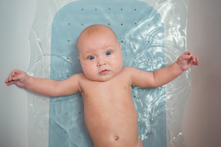Hygienic procedures for newborn. Bathing the baby in the bathroom. Happy baby in bath, top view.