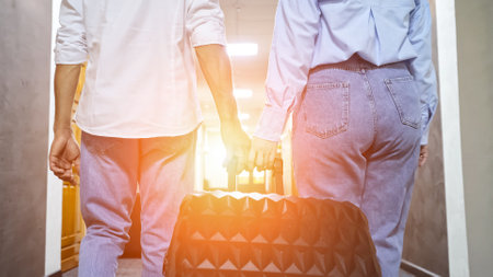 Tourist boyfriend and girlfriend with suitcase walking to reserved room in luxury hotel. Couple in anticipation from booked hotel room, sunlightの写真素材