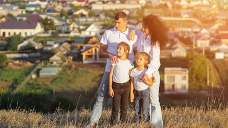 Parents point to sky drawing attention of children. Concept of family photo session and posing against populated area with residential buildings, sunlightの写真素材