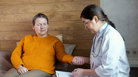 Professional nurse doing home check-up of senior woman. Practitioner listens to mature woman complaining of physical problems at home, close-uの写真素材