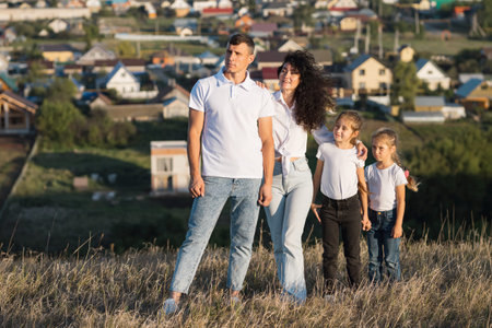 Happy family spends time usefully together outdoors. Parents with daughters stand on hills top....