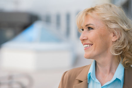 Mature woman with happy expression on face. Blonde businesswoman in beige blazer enjoying being independent executive managerの写真素材