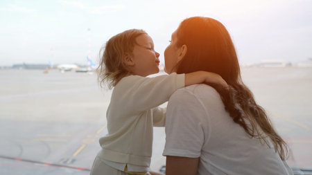 Mother and daughter interacting and showing affection at the airport, waiting for their flight