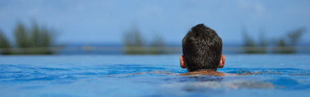Tourist enjoying the view of the ocean from a beautiful infinity pool during summer vacationの写真素材