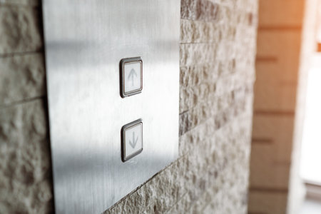 Close up of elevator buttons indicating up and down directions on a brushed metal panel beside a...