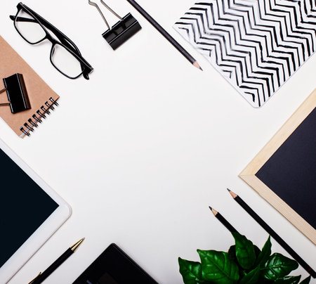 On a white background notepads, pencils, pens, greens, glasses. Flat lay with copy space. Business...