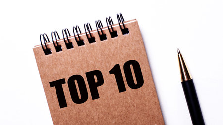 TOP-10 written on a brown notebook next to a black pen on a light background
