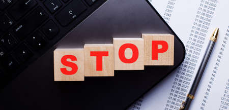 The word STOP is written in red on wooden cubes on the keyboard near the report and pen. Prohibiting conceptの写真素材