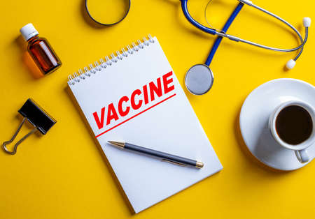The word VACCINE is written in a white locot on a yellow background near the medical concept. Close-up from aboveの写真素材