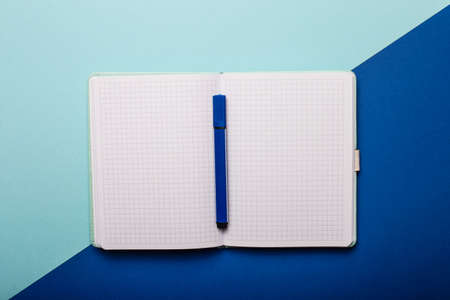 On a light blue and blue background - an open blank notebook with a blue marker. Copy spaceの写真素材