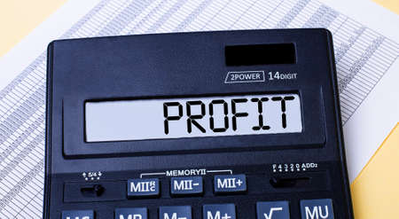 A calculator labeled PROFIT is on the table near the report. Financial conceptの写真素材