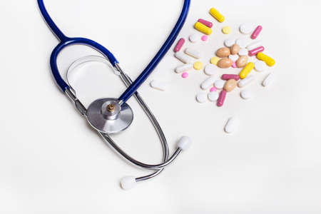 A stethoscope and multi-colored pills lie on a light background. Medical conceptの写真素材