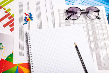 On the table are reports, a blank white sheet of paper with a pen, glasses. Workplace close-up. Copy spaceの写真素材
