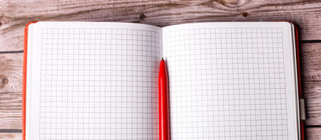 On a wooden background lies an empty open notebook and a red pen. Copy space.の写真素材