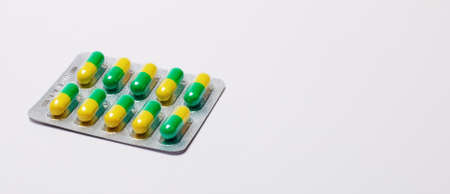 Yellow - green pills in a package on a light background. Pharmaceuticals, antibiotics, medicines.の写真素材
