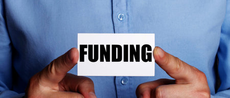 FUNDING is written on a white business card in a man's hands. Business concept