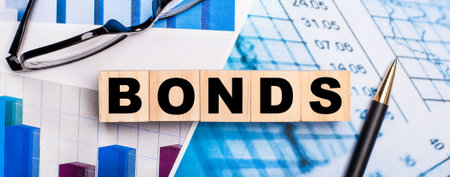 On the bright diagrams, glasses, a pen and wooden cubes with the word BONDS. Business conceptの写真素材