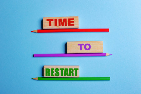 On a blue background, three colored pencils, three wooden blocks with text TIME TO RESTARTの写真素材