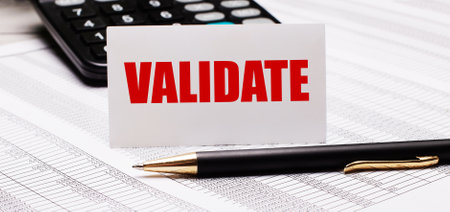 On the table there are reports, a pen, a calculator and a white card with the text VALIDATE. Defocusの写真素材