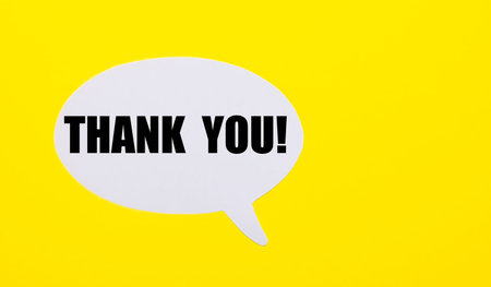 On a bright yellow background, white paper with the words THANK YOU