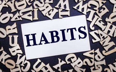 On a light background, wooden letters of the English alphabet and a white card inside with the word HABITSの写真素材