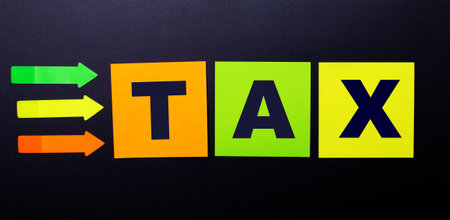 Bright multi-colored paper stickers on a black background with the text TAX ...の写真素材